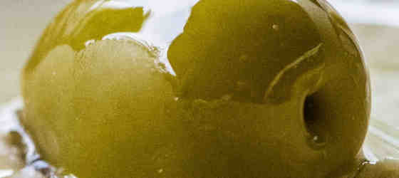Ausschnitt einer grünen Olive mit gläzendem Olivenoel-Spezialitaeten